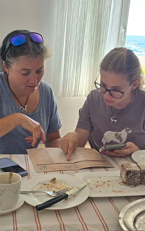 two women at a dining table looking and pointing at an offical FCI pedigree